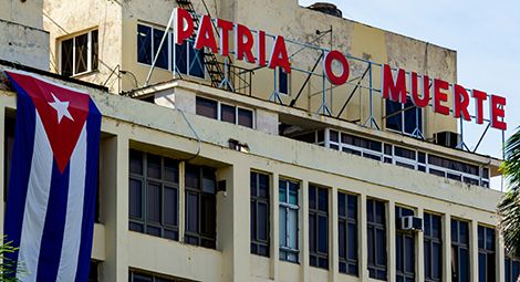 Government building with slogan overlooking Plaza 13 de Marzo in Havana, Cuba.