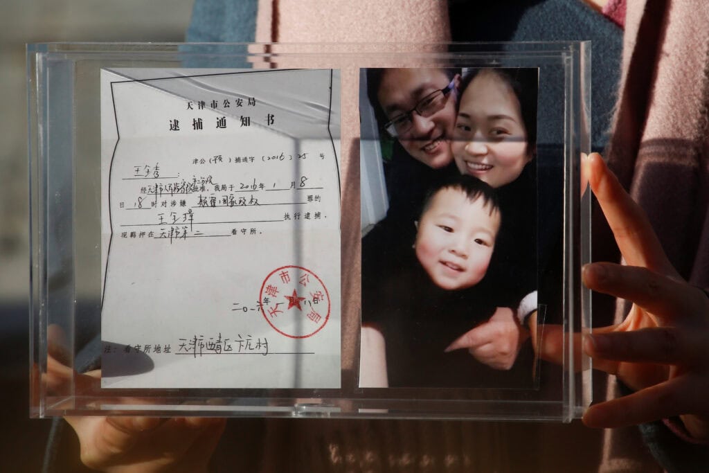Li Wenzu holds family picture and husband’s detention notice in Beijing