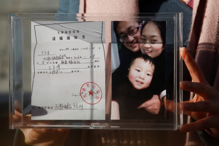 Li Wenzu holds family picture and husband’s detention notice in Beijing