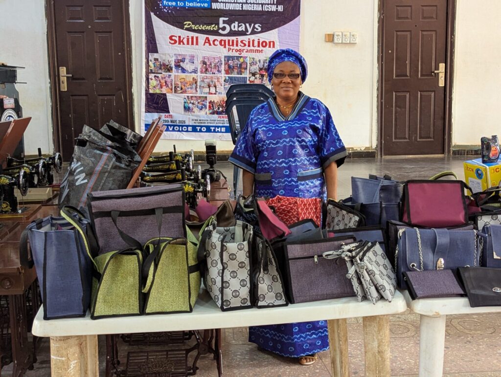 NGA CSW Nigeria skills training. Wife of CSW Trustee looks at bags produced by the participants